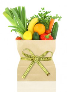 Fresh vegetables and fruits in a paper grocery bag with measuring tape